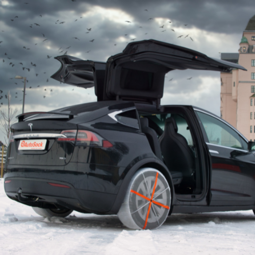AutoSock für PKW montiert auf Hinterrädern eines Autos mit Flügeltüren